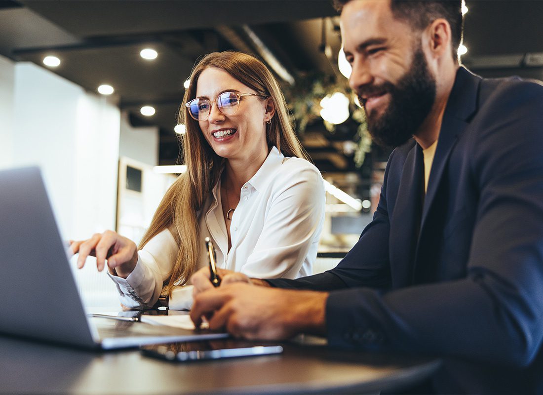 About Our Agency - Cheerful Businesspeople Using a Laptop in an Office